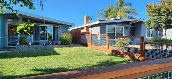 Redwood-framed silver hog wire fence running along the side yard of a blue mid-century home in Livermore, CA