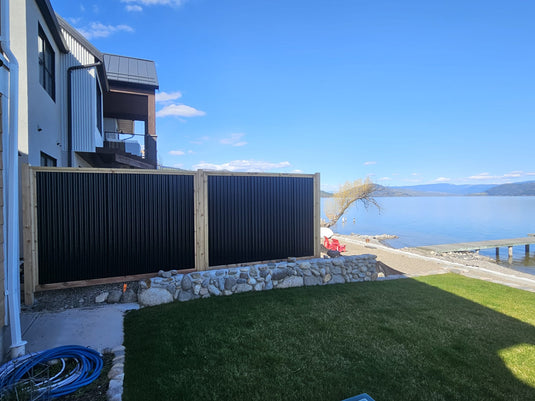 Black corrugated metal fence in coastal community, blocking main floor windows