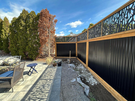 Modern backyard featuring deep groove corrugated steel privacy fence in Midnight Black with hog wire topper