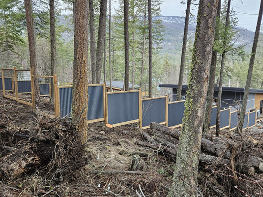 Corrugated steel fencing installed on sloping terrain.
