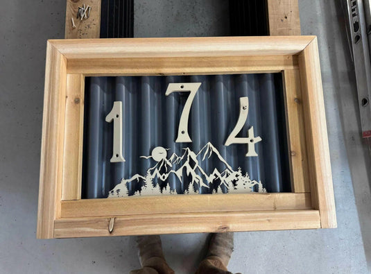 Modern house number sign with numbers mounted on corrugated panel.