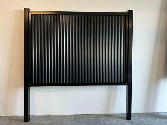 Black steel fence posts installed with corrugated metal panels