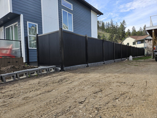 Black metal fence with reinforced metal posts surrounding modern yard.