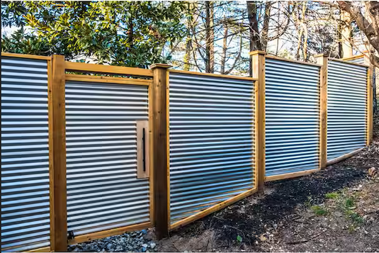 Corrugated steel privacy fence in sloping backyard.