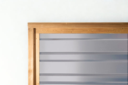 Close up of silver corrugated metal fencing in treated wood frame.