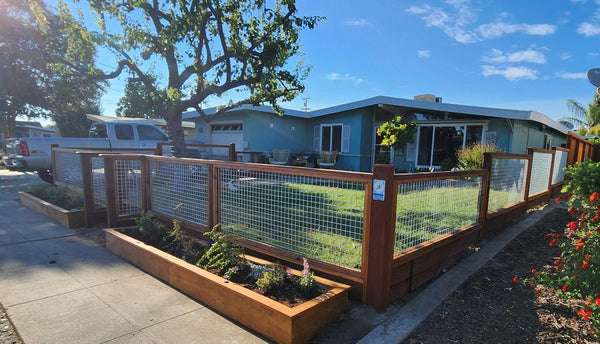 Corner of a silver hog wire and redwood fence with tiered planter boxes wrapping a Livermore, CA front yard