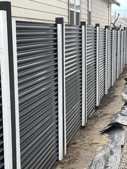 Black corrugated metal fence with black and white metal posts