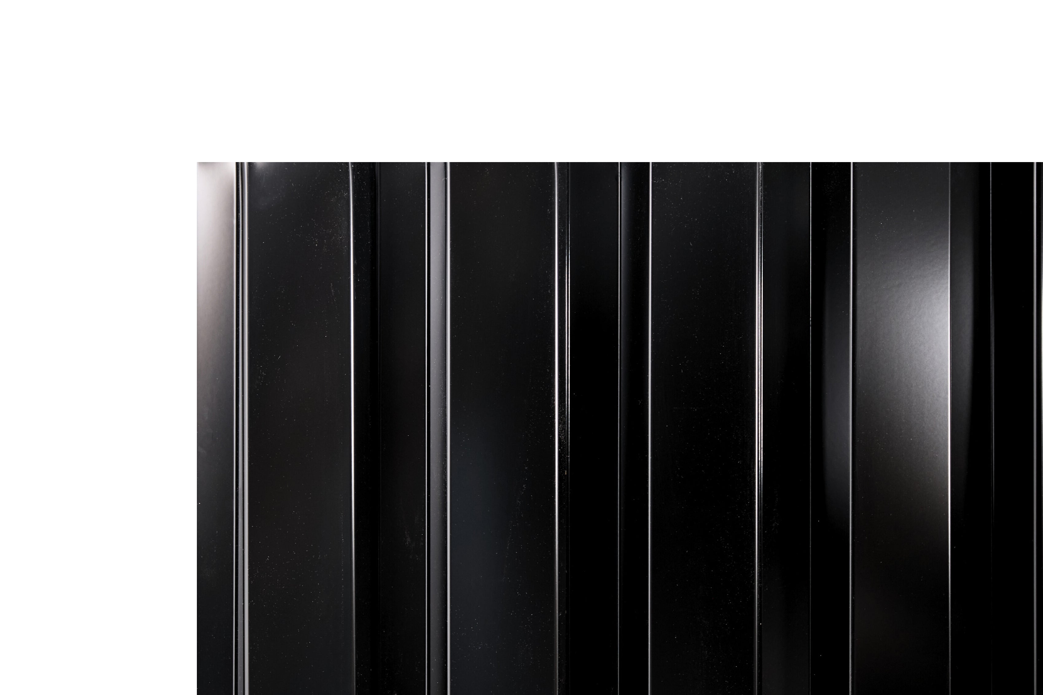 Ribbed deep-groove metal fence panel with bold vertical channels in midnight black