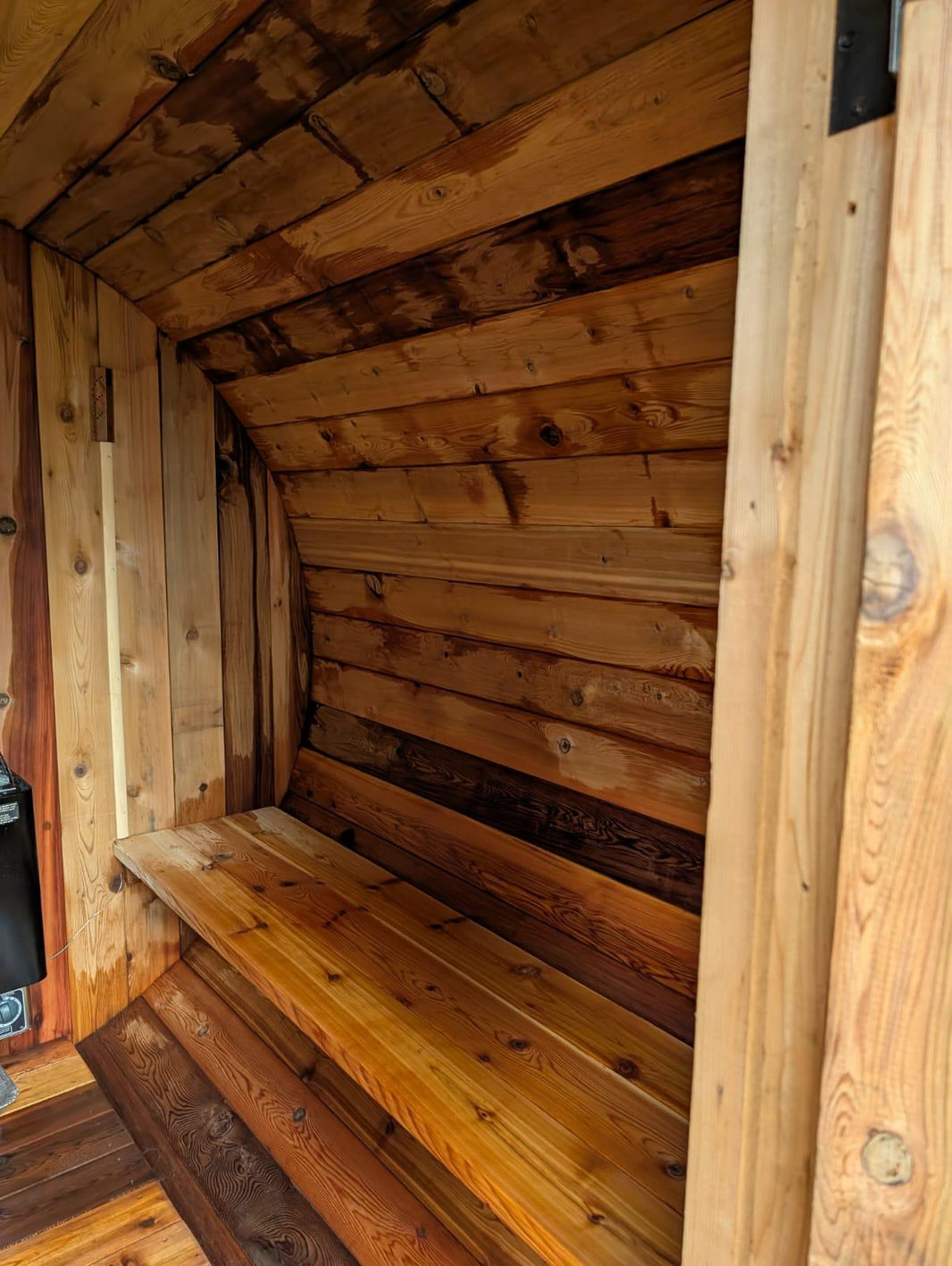 Wooden interior of a sauna with a bench and ceiling.