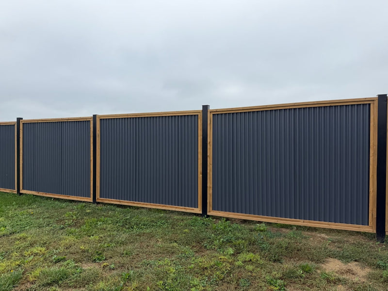 Load image into Gallery viewer, Black metal fence posts supporting cedar-framed corrugated metal fence panels
